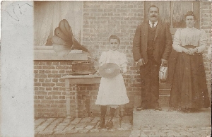 Postcard, whose date is unfortunately illegible, depicting a Phrynis phonograph with asymmetrical pavilion. The family seems very proud, the girl presents a record.